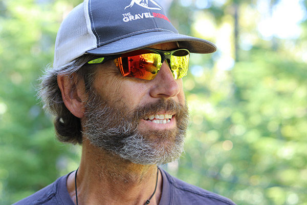 man smiling with beard, hat and sunglasses